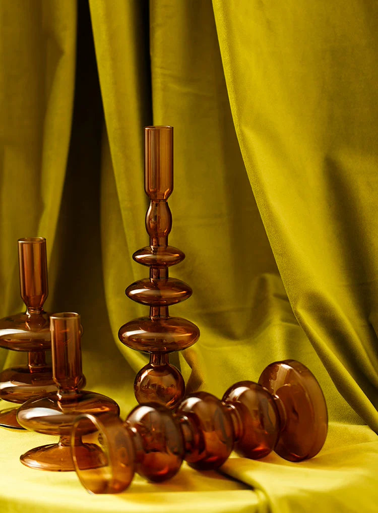 A brown glass Rhea Candle Holder set, featuring four different silhouettes in various sizes, creating a warm and inviting retro ambiance.