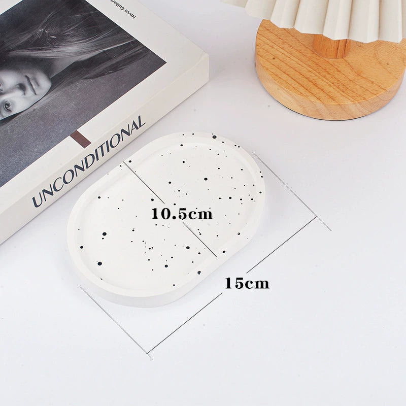 A collection of plaster trays from the Quinto Tray Collection, featuring various shapes and neutral colorways, suitable for use in different areas of the home.
