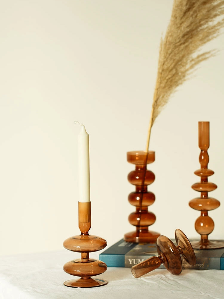 A brown glass Rhea Candle Holder set, featuring four different silhouettes in various sizes, creating a warm and inviting retro ambiance.