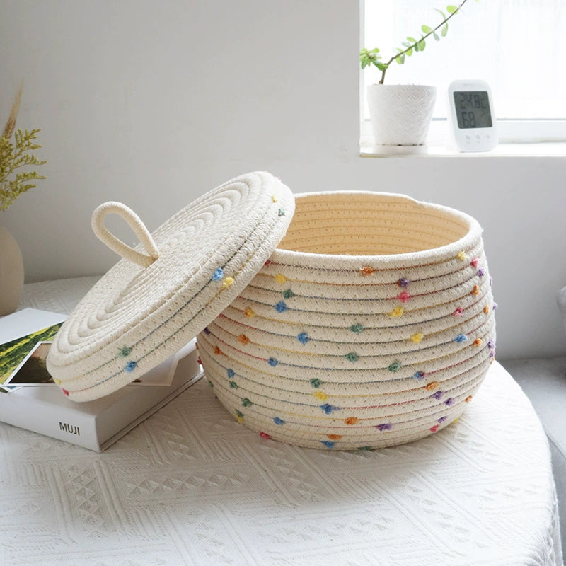 Kids' cream basket with colorful pom poms for toy and clothing storage.