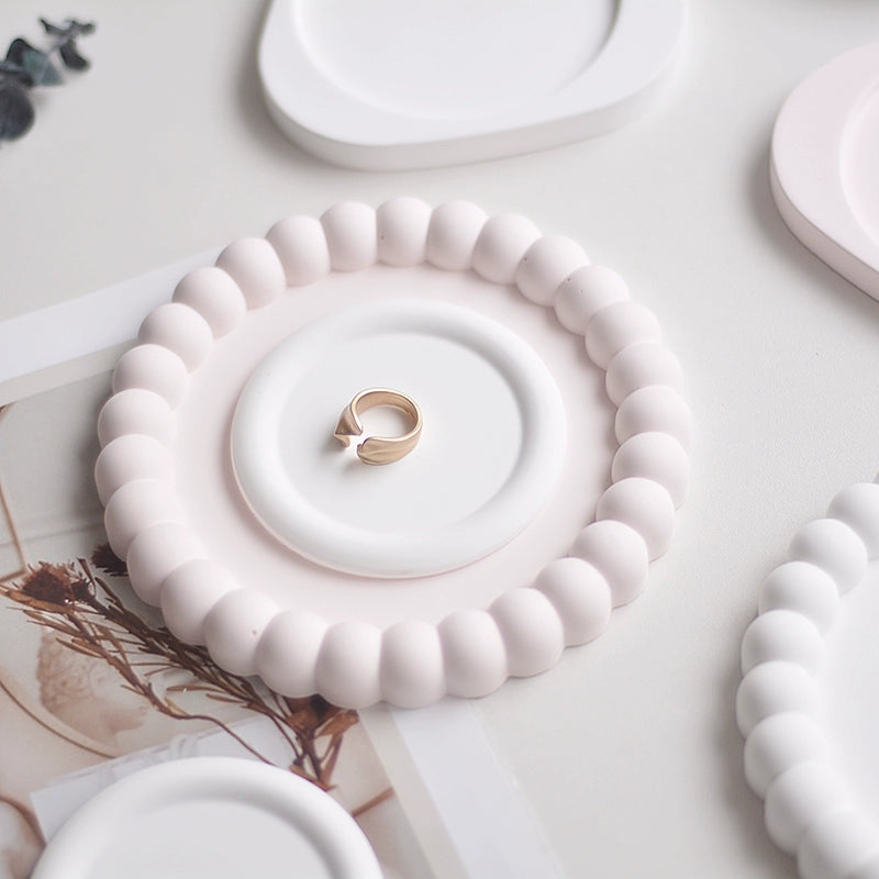 A collection of plaster trays from the Quinto Tray Collection, featuring various shapes and neutral colorways, suitable for use in different areas of the home.