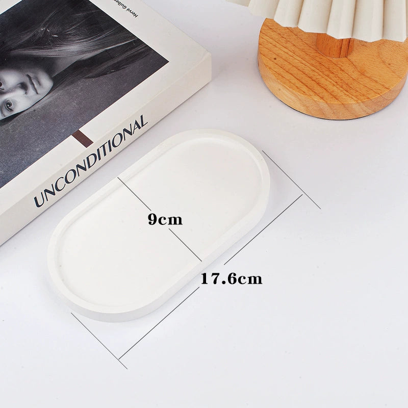 A collection of plaster trays from the Quinto Tray Collection, featuring various shapes and neutral colorways, suitable for use in different areas of the home.