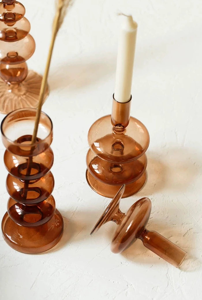 A brown glass Rhea Candle Holder set, featuring four different silhouettes in various sizes, creating a warm and inviting retro ambiance.