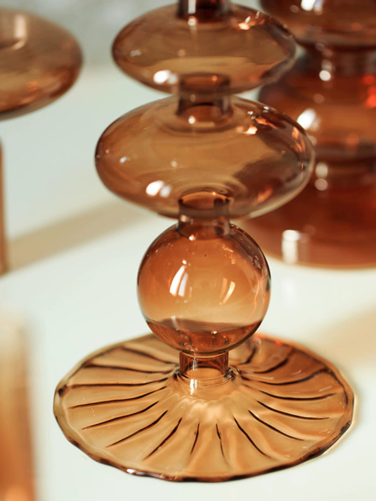 A brown glass Rhea Candle Holder set, featuring four different silhouettes in various sizes, creating a warm and inviting retro ambiance.