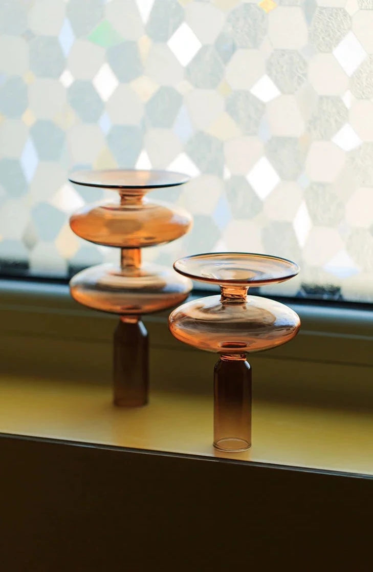A brown glass Rhea Candle Holder set, featuring four different silhouettes in various sizes, creating a warm and inviting retro ambiance.