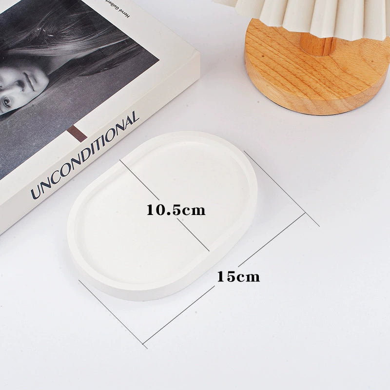A collection of plaster trays from the Quinto Tray Collection, featuring various shapes and neutral colorways, suitable for use in different areas of the home.