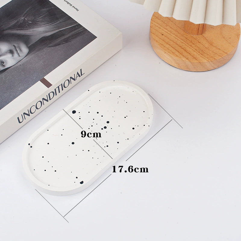 A collection of plaster trays from the Quinto Tray Collection, featuring various shapes and neutral colorways, suitable for use in different areas of the home.
