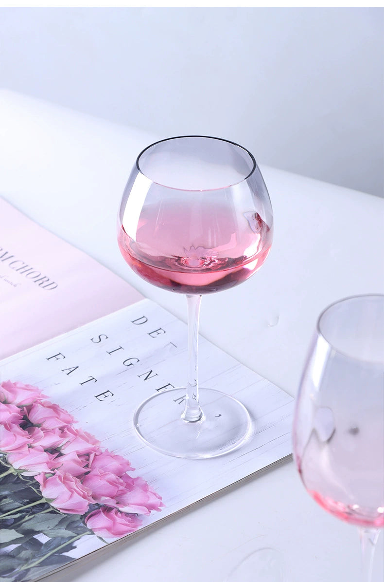 A collection of iridescent glassware from Domus Forge, featuring wine glasses, champagne coupes, decanters, and highball glasses in pastel gradient hues.