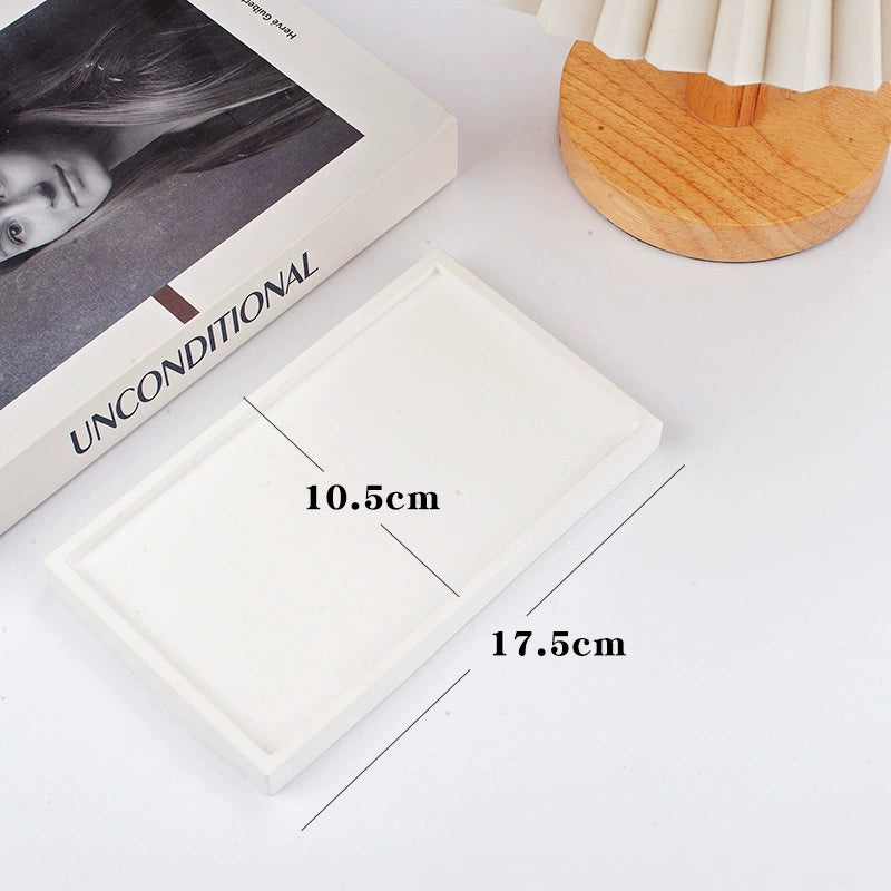 A collection of plaster trays from the Quinto Tray Collection, featuring various shapes and neutral colorways, suitable for use in different areas of the home.