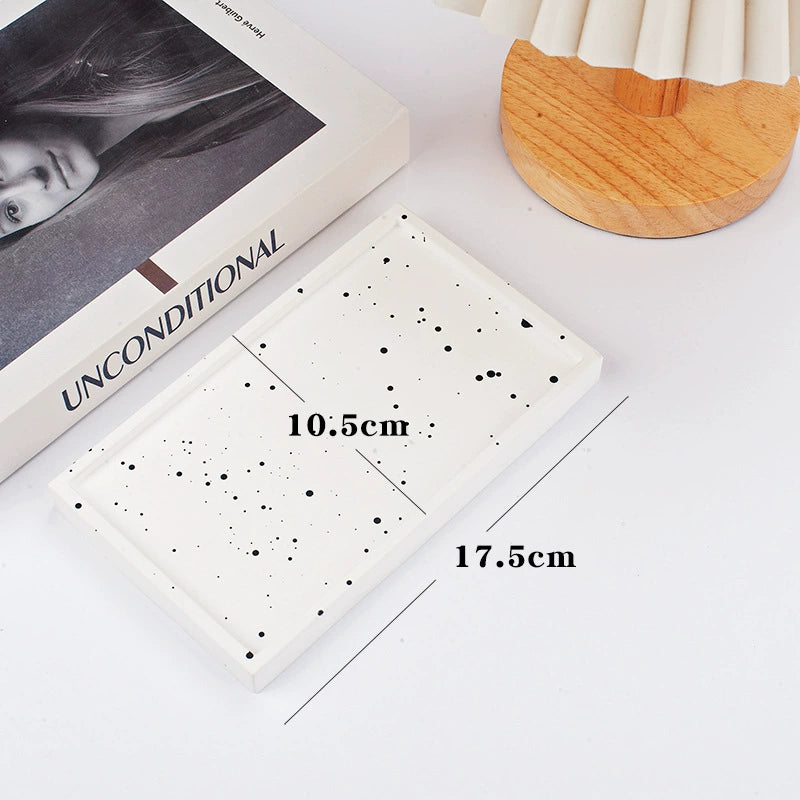 A collection of plaster trays from the Quinto Tray Collection, featuring various shapes and neutral colorways, suitable for use in different areas of the home.