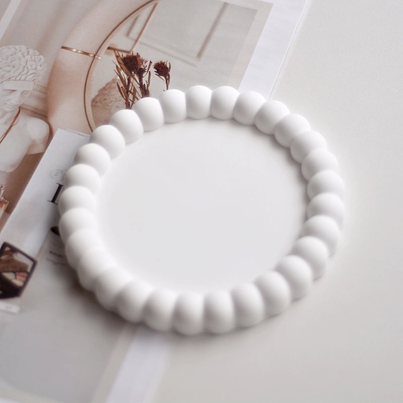 A collection of plaster trays from the Quinto Tray Collection, featuring various shapes and neutral colorways, suitable for use in different areas of the home.