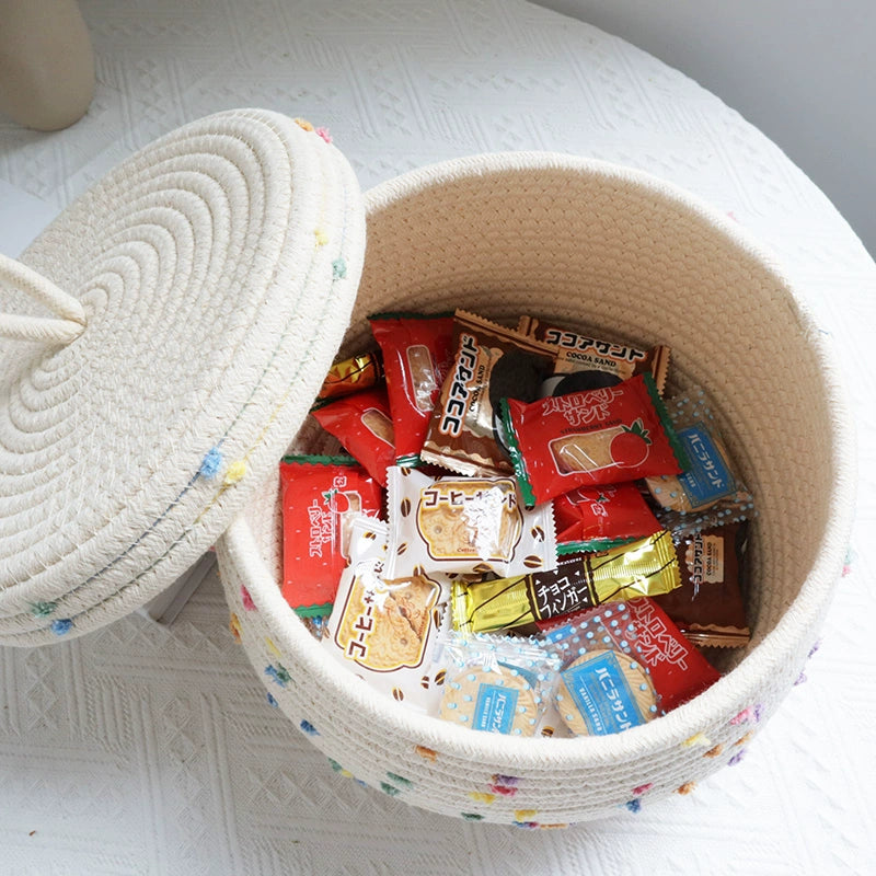 Kids' cream basket with colorful pom poms for toy and clothing storage.