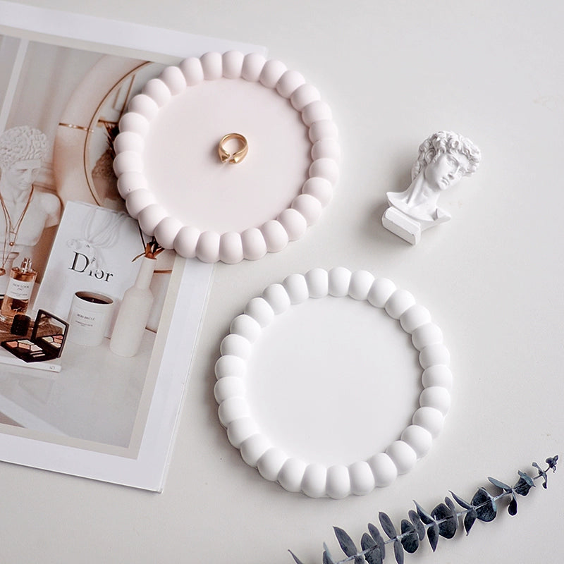 A collection of plaster trays from the Quinto Tray Collection, featuring various shapes and neutral colorways, suitable for use in different areas of the home.