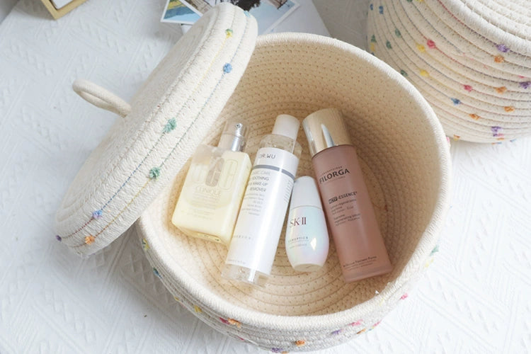 Kids' cream basket with colorful pom poms for toy and clothing storage.
