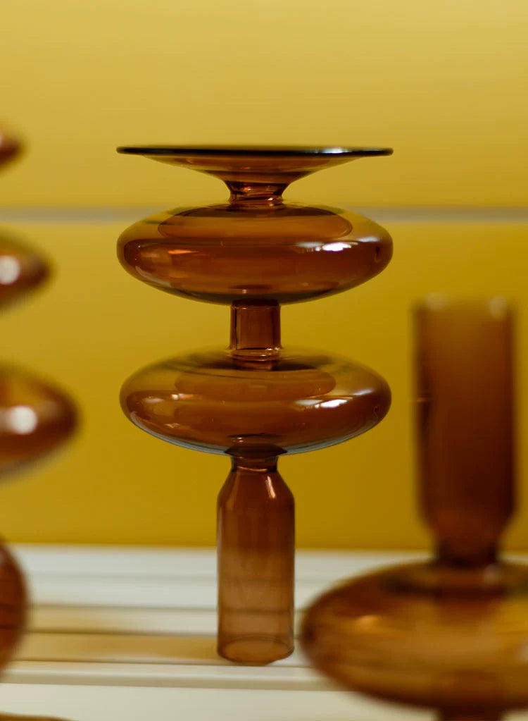 A brown glass Rhea Candle Holder set, featuring four different silhouettes in various sizes, creating a warm and inviting retro ambiance.