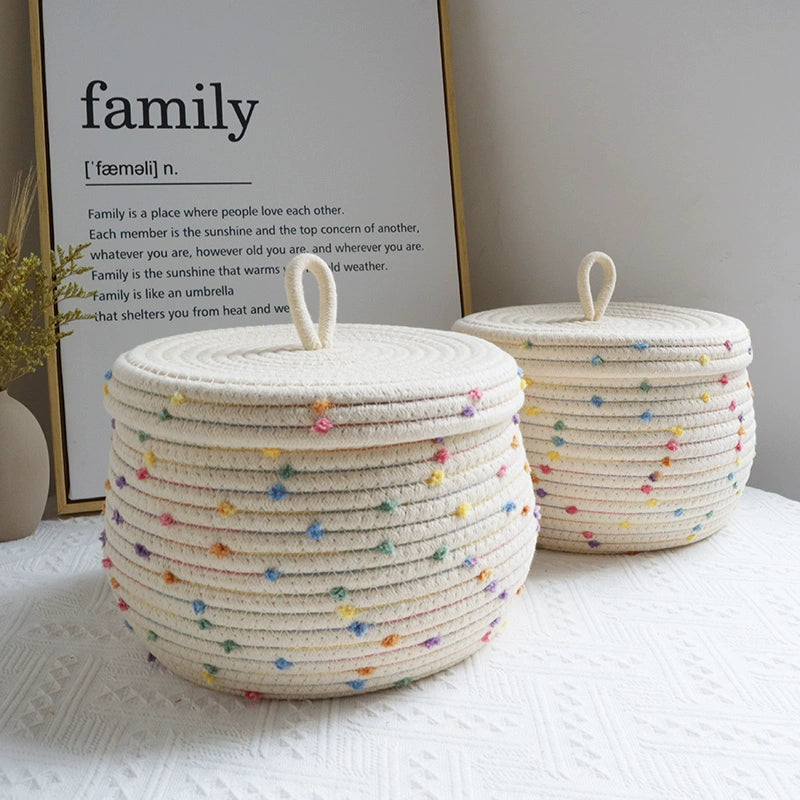 Kids' cream basket with colorful pom poms for toy and clothing storage.