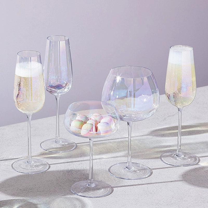 A collection of iridescent glassware from Domus Forge, featuring wine glasses, champagne coupes, decanters, and highball glasses in pastel gradient hues.