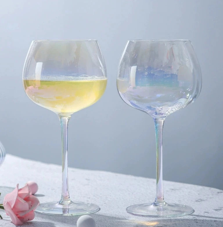 A collection of iridescent glassware from Domus Forge, featuring wine glasses, champagne coupes, decanters, and highball glasses in pastel gradient hues.