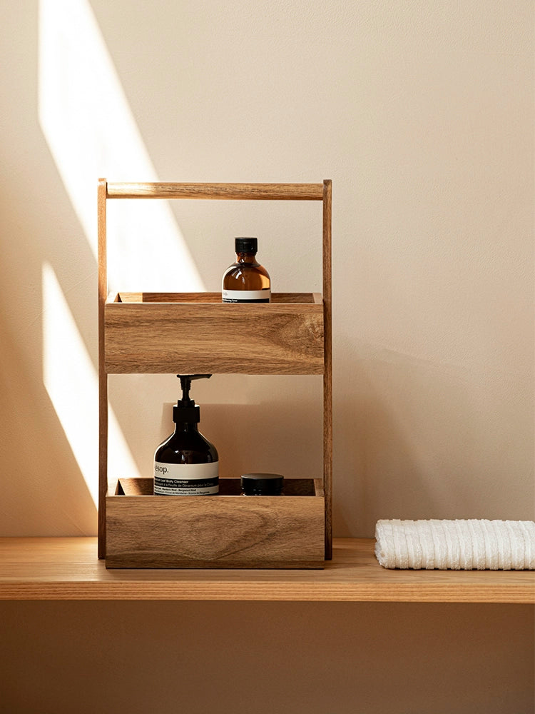 The Jacko Storage Rack features two levels made from solid acacia wood with a warm brown tone. Its simple and minimalist design makes it perfect for organizing countertops in kitchens, bathrooms, or any room in the home. This compact and stylish storage rack helps declutter while adding a touch of natural elegance, ideal for home décor enthusiasts seeking both functionality and aesthetic appeal.