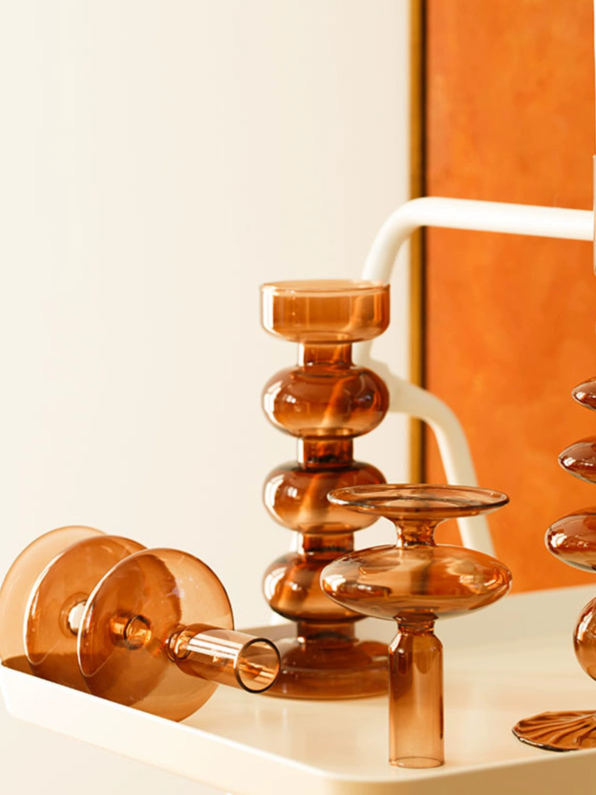 A brown glass Rhea Candle Holder set, featuring four different silhouettes in various sizes, creating a warm and inviting retro ambiance.