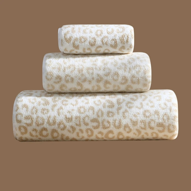 A chic set of Teagan Leopard Towels displayed in a bathroom. The towels feature a stylish leopard print in neutral tones, made from soft, absorbent cotton. The set includes a large bath towel, a hand towel, and a washcloth, offering versatility for different uses. The towels are quick-drying and designed to blend seamlessly with various bathroom decors, perfect for home décor enthusiasts seeking both functionality and style.