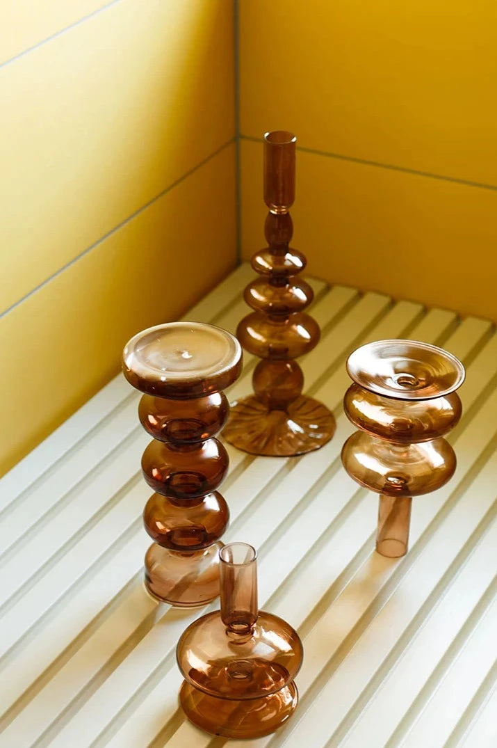 A brown glass Rhea Candle Holder set, featuring four different silhouettes in various sizes, creating a warm and inviting retro ambiance.