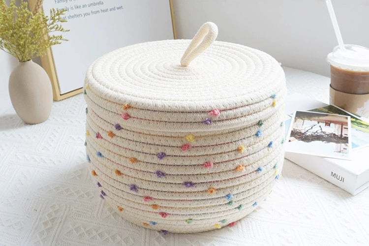 Kids' cream basket with colorful pom poms for toy and clothing storage.