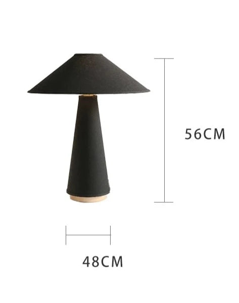 A minimalist table lamp in either black or white color options, available in small or large sizes. The lamp features a seamless design with the base and shade made from the same material, providing a warm and simple aesthetic with a subtle linen texture.