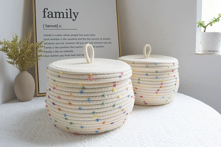 Kids' cream basket with colorful pom poms for toy and clothing storage.