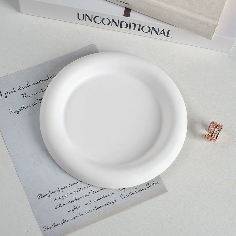 A collection of plaster trays from the Quinto Tray Collection, featuring various shapes and neutral colorways, suitable for use in different areas of the home.