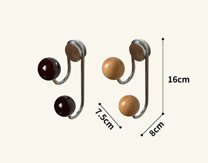 Magnetic hooks with a sleek silver wrought iron base and warm wooden ball accents. The Sau Magnet Hooks are available in two colorways and are designed for use on metal surfaces in kitchens, bathrooms, or locker rooms. Ideal for home decor enthusiasts seeking a stylish, modern storage solution.