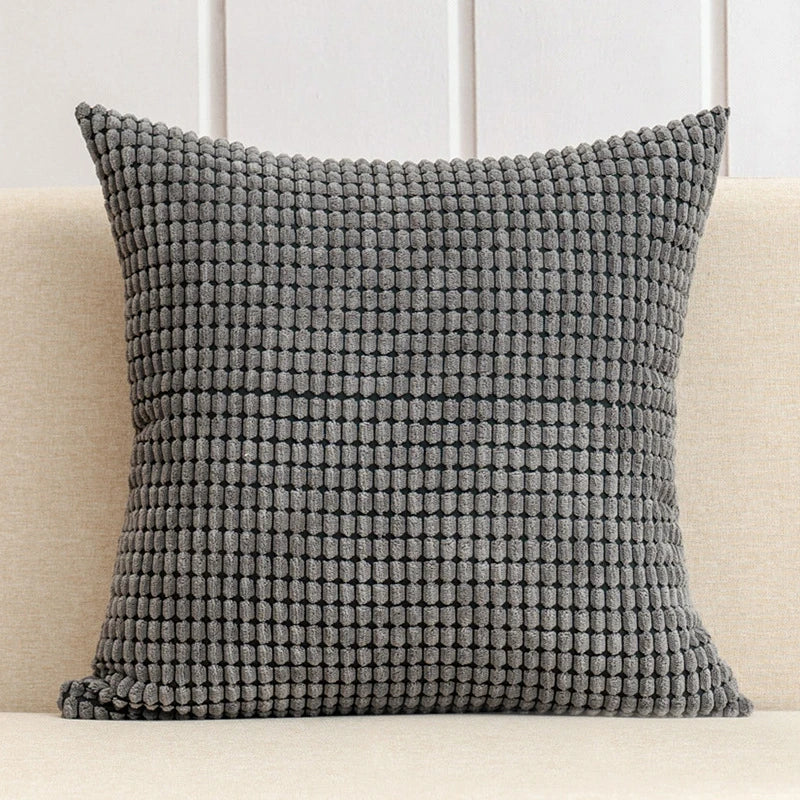 A stylish Warren Pillow Cover displayed on a couch, showcasing its soft corduroy corn grain texture. Available in various colorways and sizes, this square pillow cover adds warmth and elegance to any space. Ideal for home décor enthusiasts, it enhances living areas with a cozy, inviting touch. Please note that the pillow insert is not included.