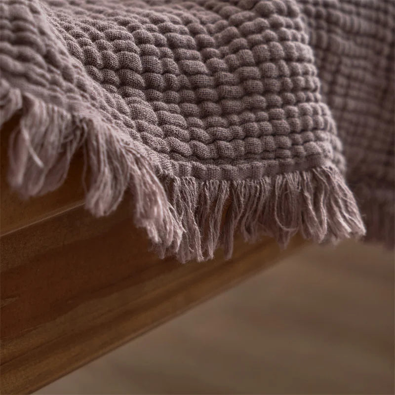 Nogu Throw Blanket – soft Maillard cotton throw with a layered gauze texture, fringe detail, and chic muted colorways, available in two sizes for cozy, stylish comfort.