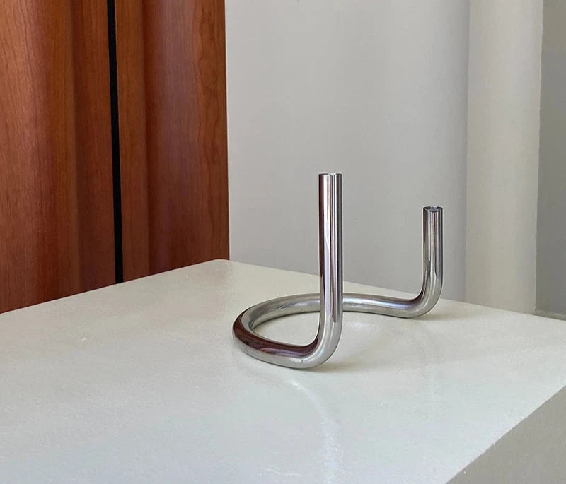The Ivy Candle Holder features a modern, U-shaped stainless steel design that holds two candles. With a sleek, minimalist look, it is perfect for home décor enthusiasts who love contemporary accents. Ideal for creating a stylish ambiance on dinner tables, mantles, or living spaces, this candle holder blends functionality and elegance.