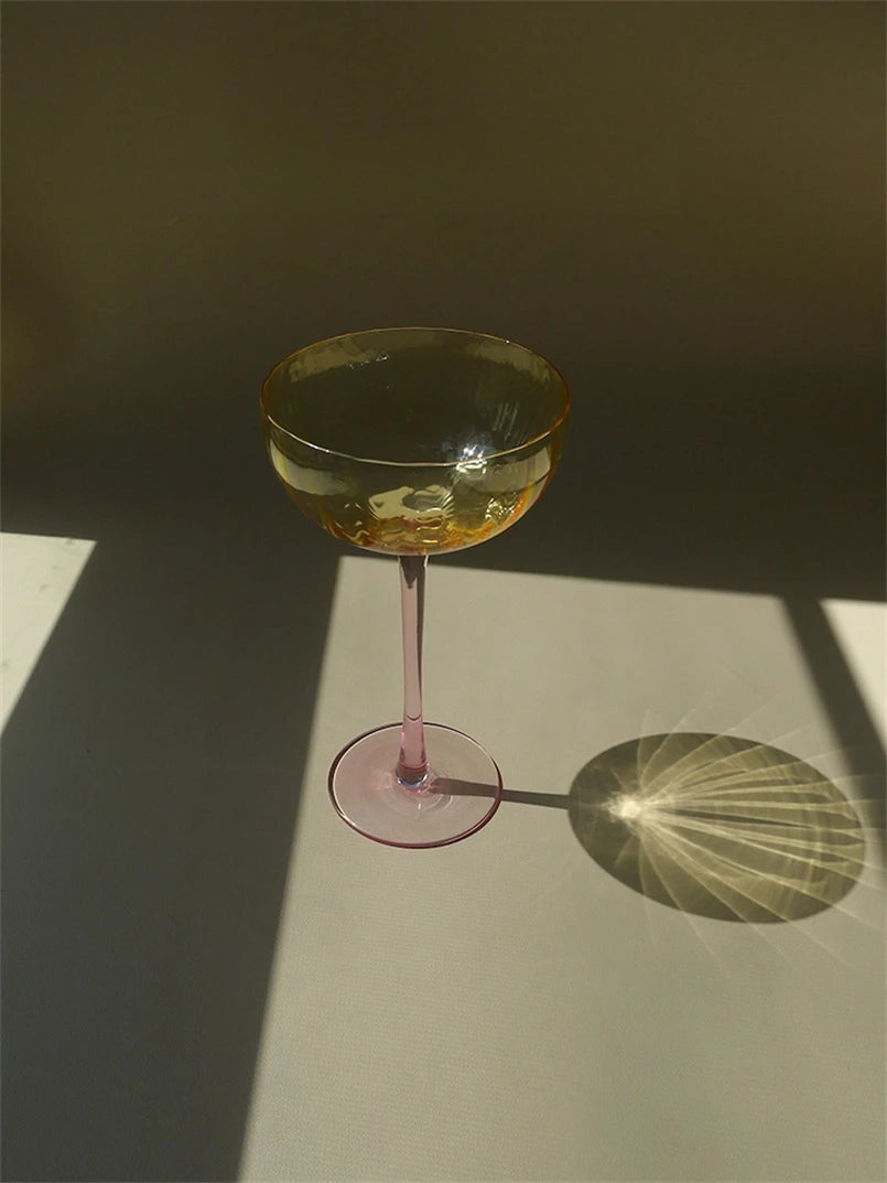 A vibrant collection of Ugo Wine Glasses displayed on a table, showcasing their fun and chic design. Each glass features a colored pastel bowl with a contrasting stem and a fluted shape. Ideal for entertaining, these glasses hold 11 fluid ounces and are perfect for mixing and matching. Designed for home décor enthusiasts, they add a playful yet elegant touch to any bar or dining setting.