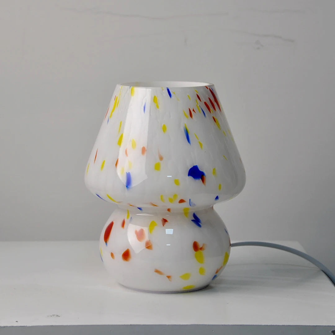 Carson Table Lamp – small mushroom-shaped glass lamp with a white base and colorful ink splat design, casting a soft, warm light for a playful and cozy ambiance.