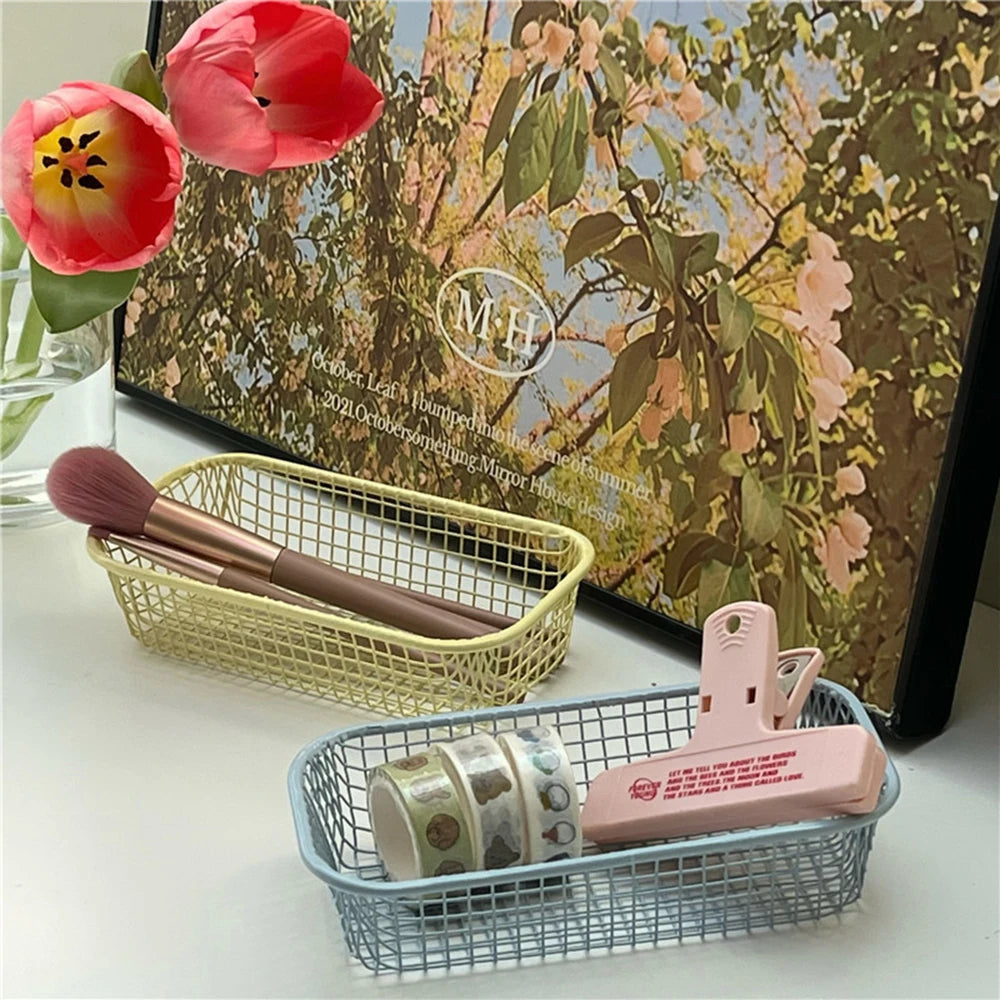 A small, versatile Elon Storage Basket displayed in a minimalist setting. The basket, made of durable metal, comes in butter yellow, sky blue, and navy. It is ideal for various uses, including organizing kitchen essentials, office supplies, or bath accessories. The sleek, utilitarian design complements modern and functional decor. The basket is shown in different color combinations, highlighting its mix-and-match capability for cohesive organization.