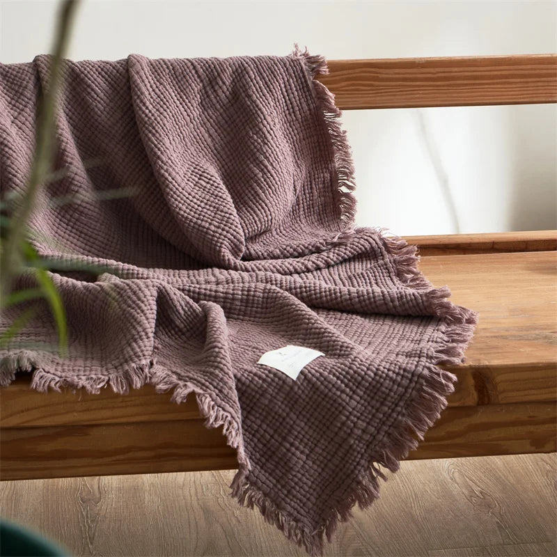 Nogu Throw Blanket – soft Maillard cotton throw with a layered gauze texture, fringe detail, and chic muted colorways, available in two sizes for cozy, stylish comfort.