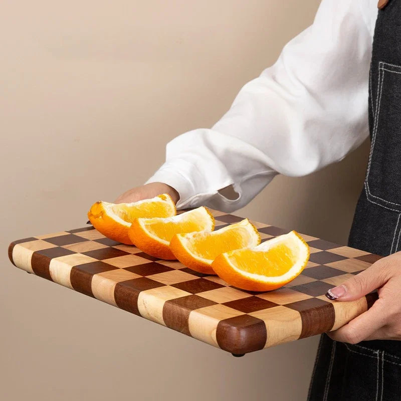Rectangular wooden cutting board with a checkerboard pattern, available in three sizes. Features rounded corners and non-slip rubber feet, used for both meal prep and serving as a cheese board or decorative kitchen display.