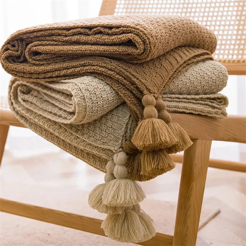 Image of the Soma Throw Blanket, featuring a cozy, soft fleece and cotton blend with a waffled texture. Available in various colorways and three sizes, this throw blanket has elegant tasseled corners and a knitted design, perfect for home décor enthusiasts looking to add comfort and style to their living space.