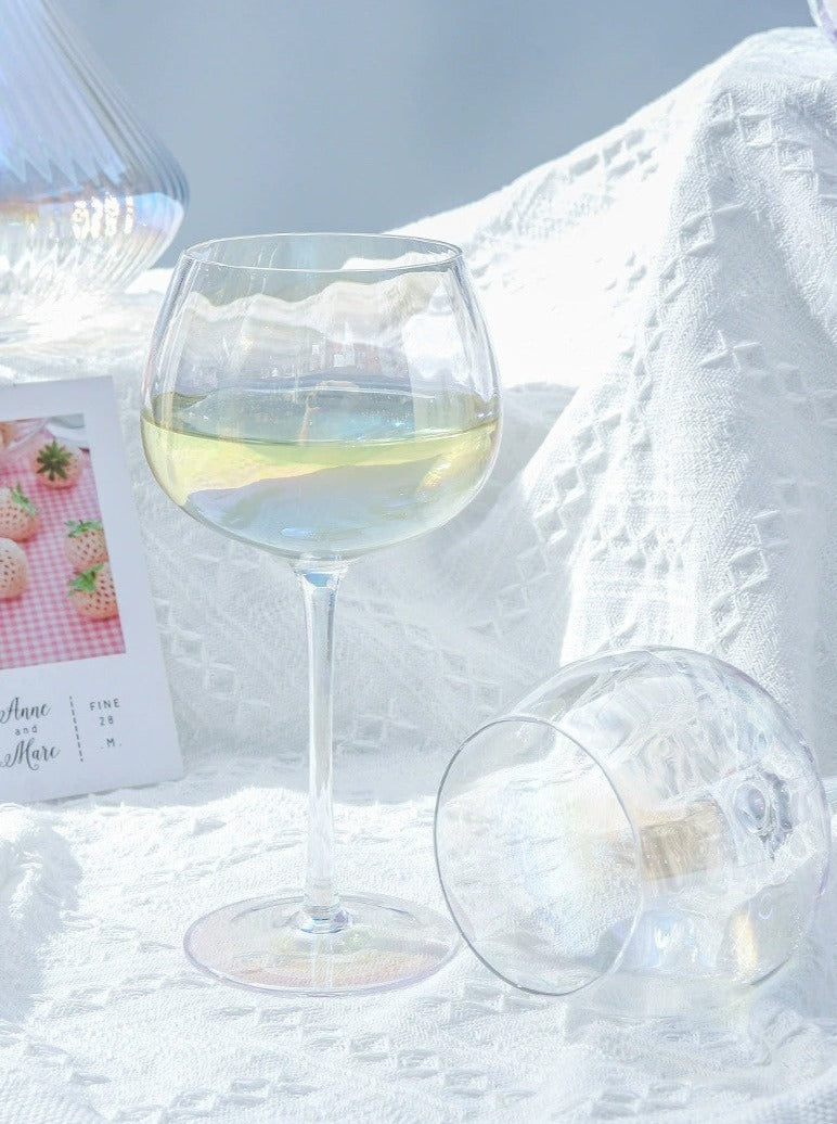 A collection of iridescent glassware from Domus Forge, featuring wine glasses, champagne coupes, decanters, and highball glasses in pastel gradient hues.