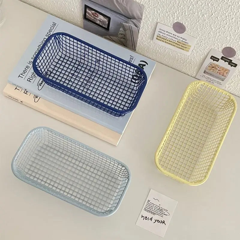 A small, versatile Elon Storage Basket displayed in a minimalist setting. The basket, made of durable metal, comes in butter yellow, sky blue, and navy. It is ideal for various uses, including organizing kitchen essentials, office supplies, or bath accessories. The sleek, utilitarian design complements modern and functional decor. The basket is shown in different color combinations, highlighting its mix-and-match capability for cohesive organization.