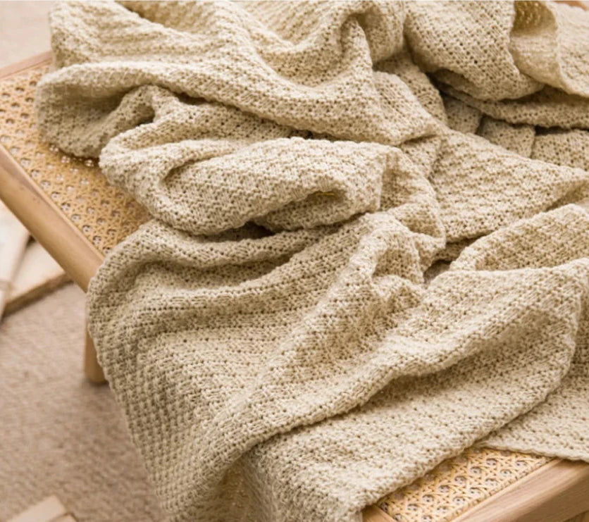 Image of the Soma Throw Blanket, featuring a cozy, soft fleece and cotton blend with a waffled texture. Available in various colorways and three sizes, this throw blanket has elegant tasseled corners and a knitted design, perfect for home décor enthusiasts looking to add comfort and style to their living space.