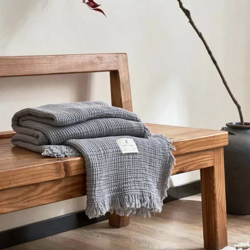 Nogu Throw Blanket – soft Maillard cotton throw with a layered gauze texture, fringe detail, and chic muted colorways, available in two sizes for cozy, stylish comfort.