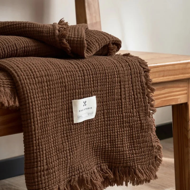 Nogu Throw Blanket – soft Maillard cotton throw with a layered gauze texture, fringe detail, and chic muted colorways, available in two sizes for cozy, stylish comfort.