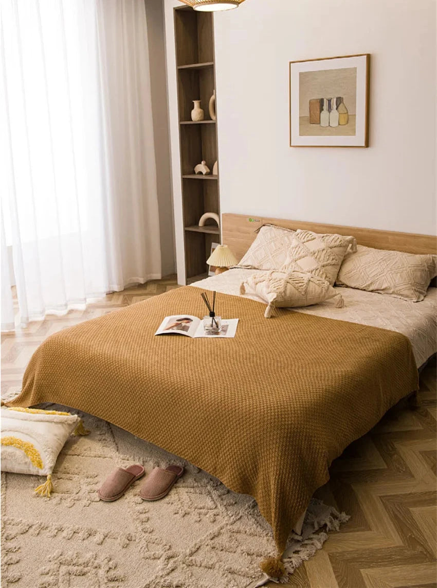 Image of the Soma Throw Blanket, featuring a cozy, soft fleece and cotton blend with a waffled texture. Available in various colorways and three sizes, this throw blanket has elegant tasseled corners and a knitted design, perfect for home décor enthusiasts looking to add comfort and style to their living space.