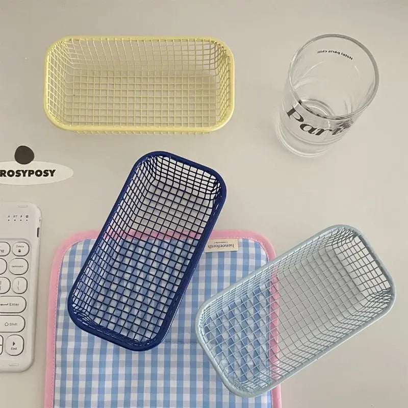 A small, versatile Elon Storage Basket displayed in a minimalist setting. The basket, made of durable metal, comes in butter yellow, sky blue, and navy. It is ideal for various uses, including organizing kitchen essentials, office supplies, or bath accessories. The sleek, utilitarian design complements modern and functional decor. The basket is shown in different color combinations, highlighting its mix-and-match capability for cohesive organization.