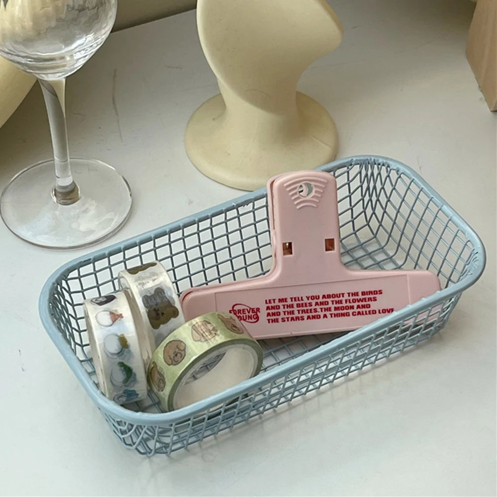 A small, versatile Elon Storage Basket displayed in a minimalist setting. The basket, made of durable metal, comes in butter yellow, sky blue, and navy. It is ideal for various uses, including organizing kitchen essentials, office supplies, or bath accessories. The sleek, utilitarian design complements modern and functional decor. The basket is shown in different color combinations, highlighting its mix-and-match capability for cohesive organization.