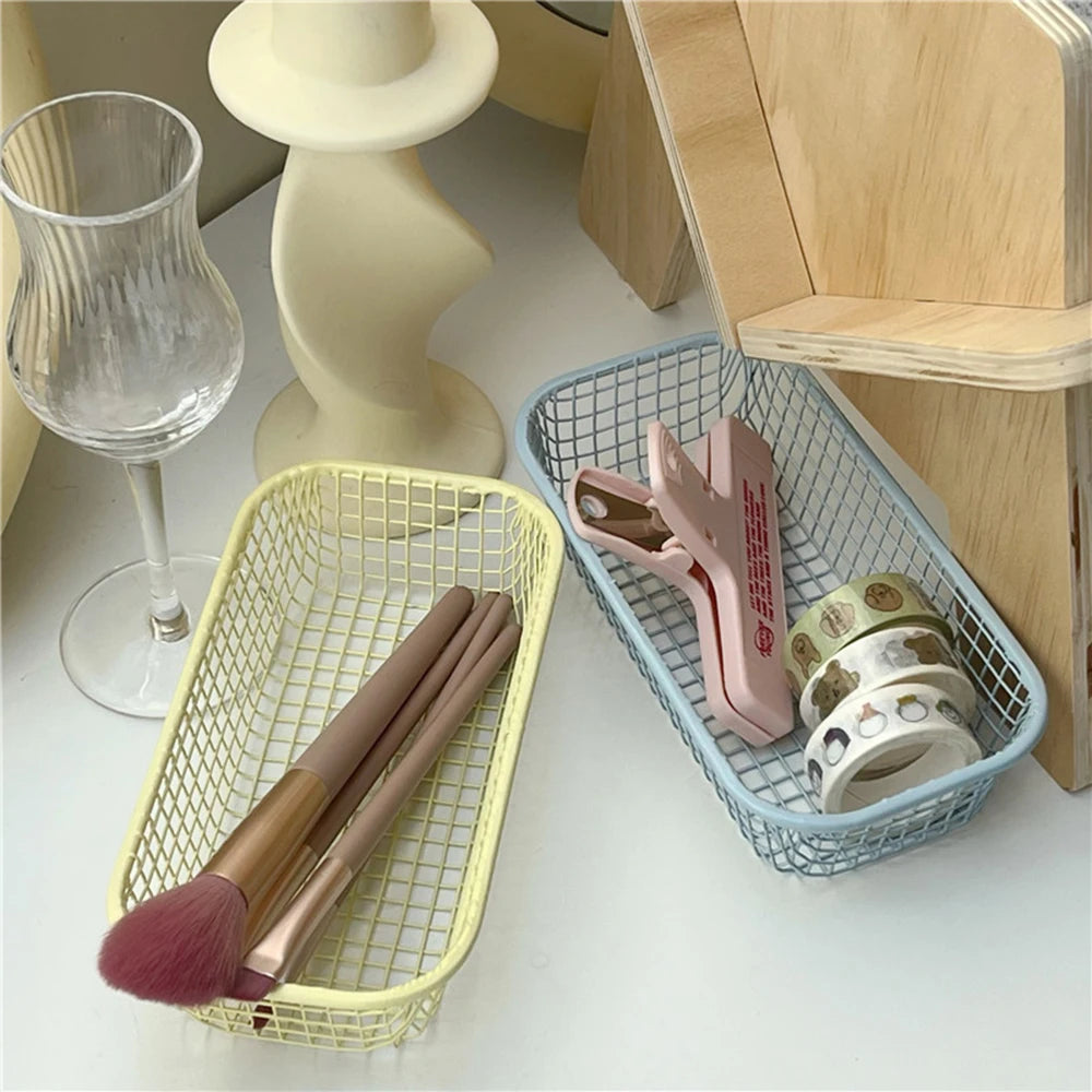 A small, versatile Elon Storage Basket displayed in a minimalist setting. The basket, made of durable metal, comes in butter yellow, sky blue, and navy. It is ideal for various uses, including organizing kitchen essentials, office supplies, or bath accessories. The sleek, utilitarian design complements modern and functional decor. The basket is shown in different color combinations, highlighting its mix-and-match capability for cohesive organization.