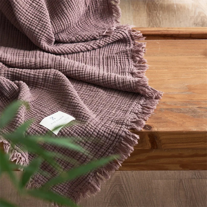 Nogu Throw Blanket – soft Maillard cotton throw with a layered gauze texture, fringe detail, and chic muted colorways, available in two sizes for cozy, stylish comfort.